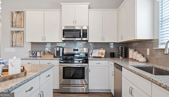 kitchen featuring white cabinets, backsplash, stainless steel appliances, and a sink