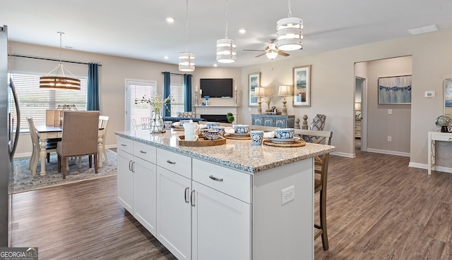 kitchen with pendant lighting, dark wood-style flooring, white cabinetry, and a kitchen bar