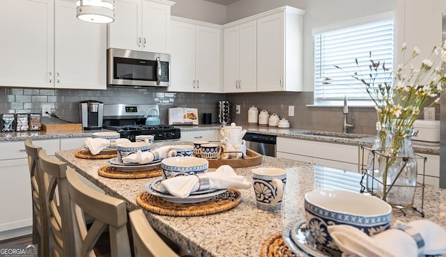 kitchen with stainless steel appliances, backsplash, a sink, and white cabinetry