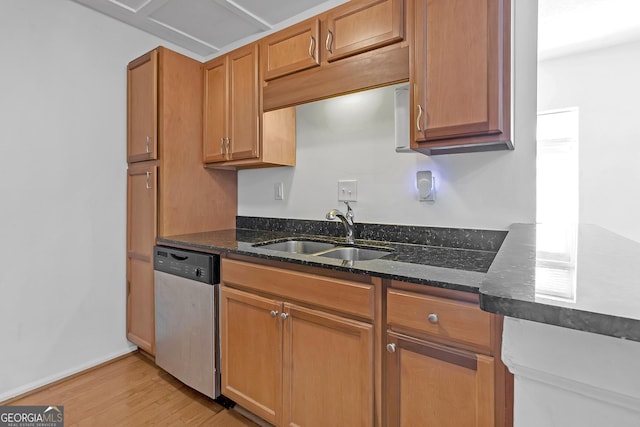 kitchen with dark stone countertops, sink, stainless steel dishwasher, and light hardwood / wood-style floors