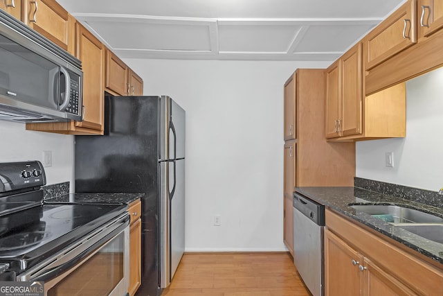 kitchen featuring sink, dark stone counters, light wood-type flooring, and appliances with stainless steel finishes