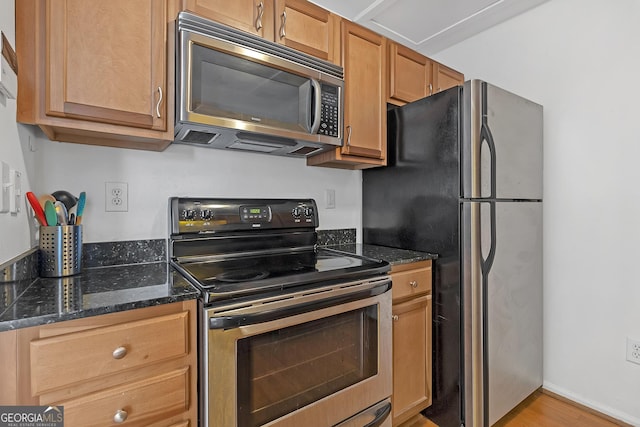 kitchen featuring dark stone countertops, light wood-type flooring, and appliances with stainless steel finishes