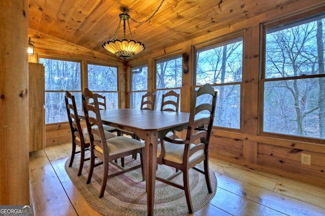 dining space featuring light hardwood / wood-style floors, vaulted ceiling, wood walls, and wood ceiling