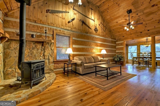 living room featuring hardwood / wood-style flooring, ceiling fan, a wood stove, and high vaulted ceiling