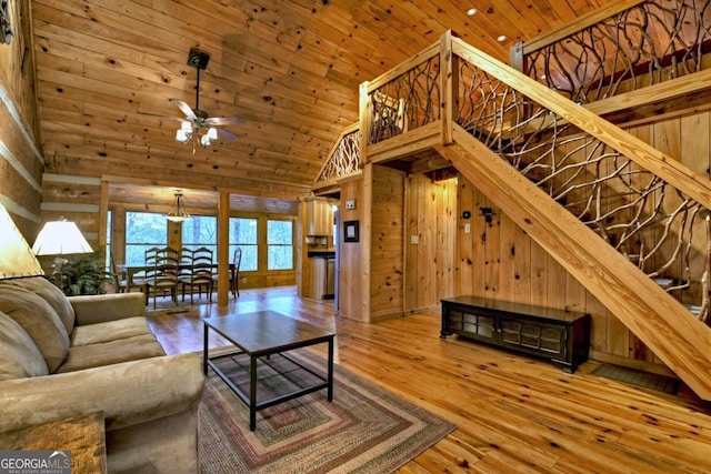 living room featuring wooden walls, hardwood / wood-style flooring, and high vaulted ceiling