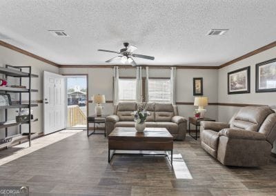 living room featuring ceiling fan, ornamental molding, a textured ceiling, and dark wood-type flooring