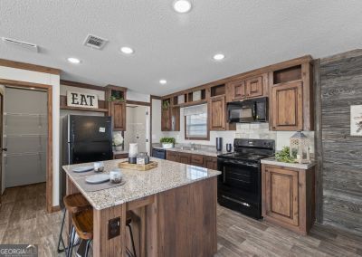 kitchen featuring a center island, a kitchen breakfast bar, a textured ceiling, black appliances, and hardwood / wood-style flooring