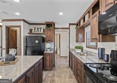 kitchen with black appliances, light stone counters, crown molding, and a textured ceiling