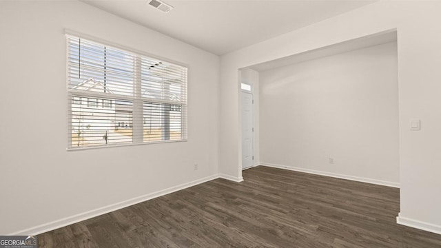 spare room with plenty of natural light and dark hardwood / wood-style floors