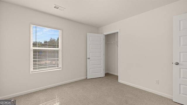 unfurnished bedroom with light colored carpet and a closet