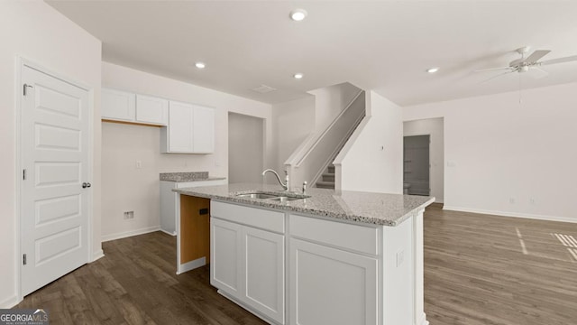 kitchen with light stone countertops, sink, ceiling fan, an island with sink, and white cabinets