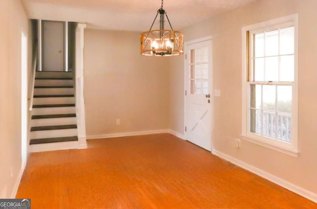 unfurnished dining area with a chandelier and wood-type flooring