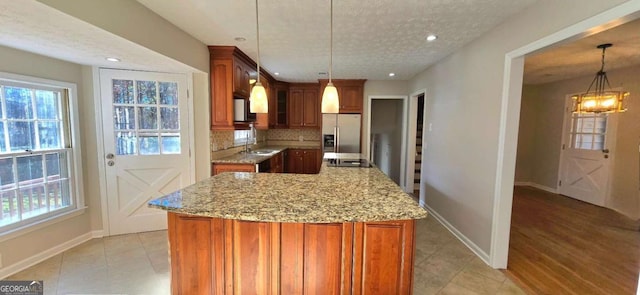 kitchen featuring stainless steel refrigerator with ice dispenser, a center island, tasteful backsplash, and pendant lighting