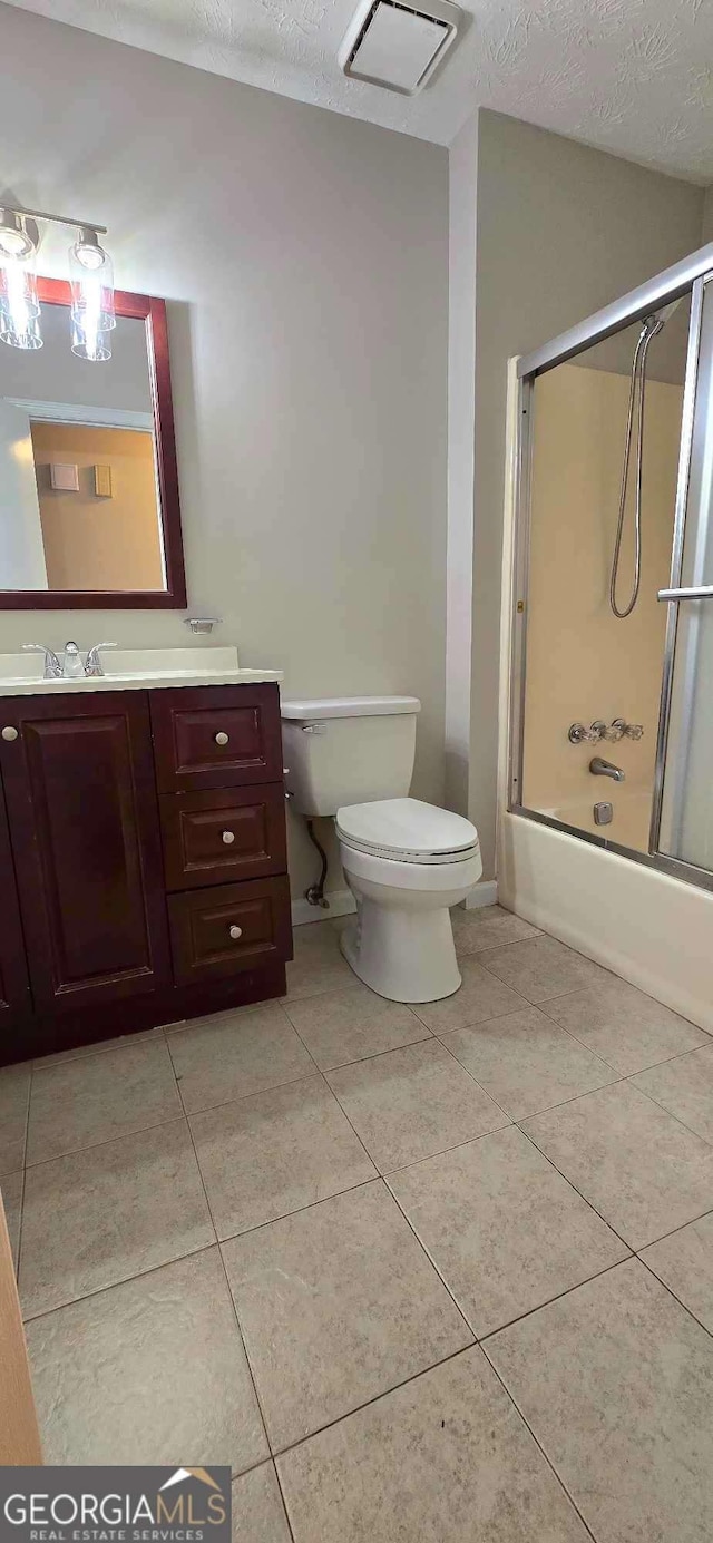 full bathroom featuring combined bath / shower with glass door, toilet, a textured ceiling, and vanity