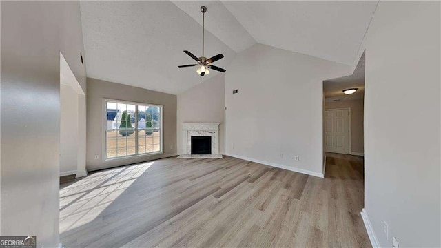 unfurnished living room with ceiling fan, a fireplace, high vaulted ceiling, and light hardwood / wood-style floors