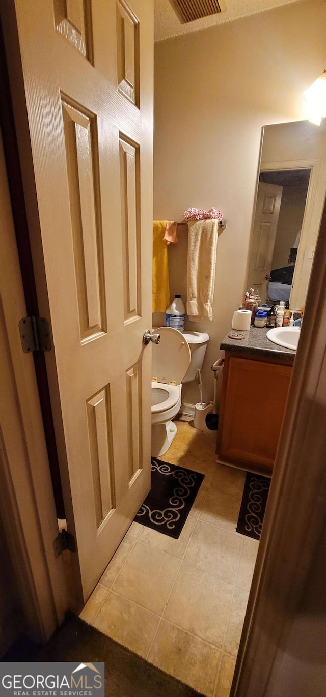 bathroom with tile patterned flooring, vanity, and toilet