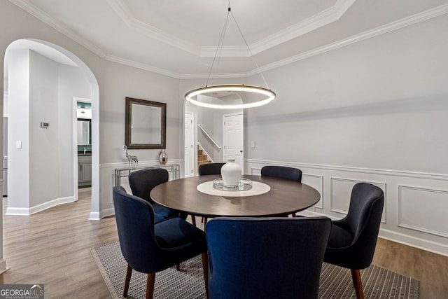 dining room featuring hardwood / wood-style flooring, a raised ceiling, and ornamental molding