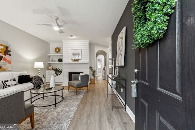 living room with ceiling fan, a fireplace, and light hardwood / wood-style flooring