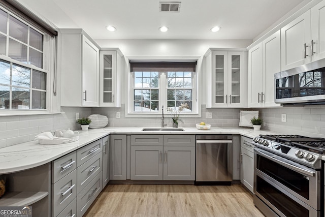 kitchen featuring white cabinetry, light stone countertops, sink, stainless steel appliances, and gray cabinets