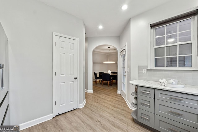 interior space featuring tasteful backsplash, gray cabinets, light stone countertops, and light hardwood / wood-style floors