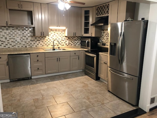 kitchen featuring appliances with stainless steel finishes, tasteful backsplash, gray cabinetry, exhaust hood, and sink