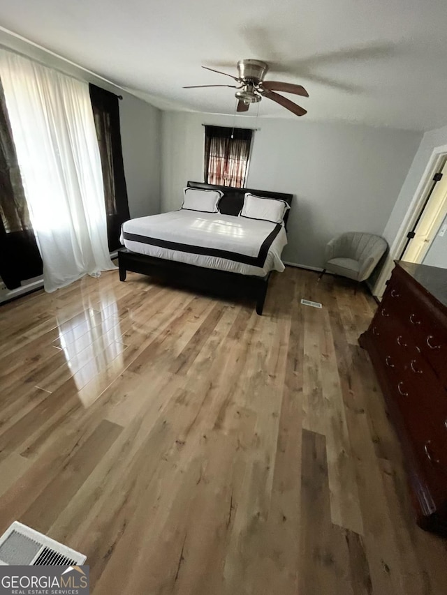 bedroom with hardwood / wood-style flooring, ceiling fan, and multiple windows