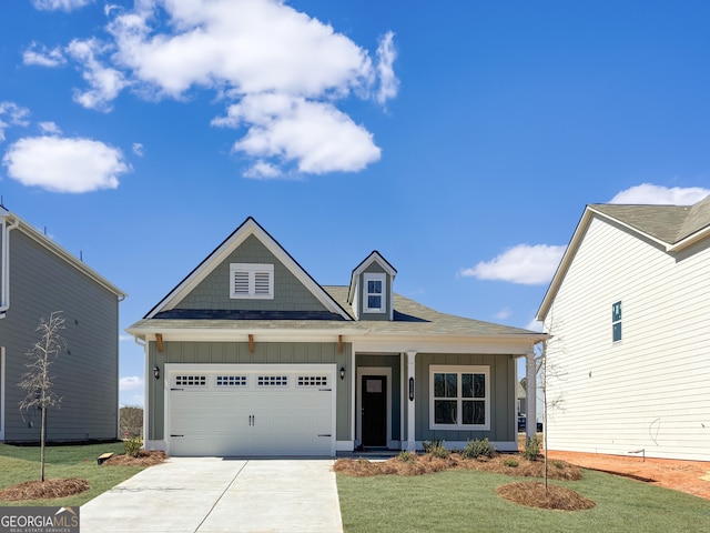 view of front of property with board and batten siding, concrete driveway, an attached garage, and a front lawn