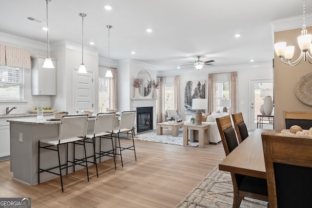 kitchen with pendant lighting, ceiling fan with notable chandelier, white cabinetry, and light stone counters