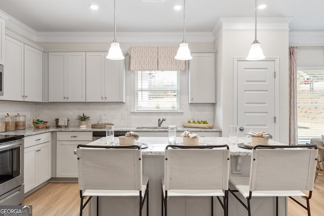 kitchen with light stone countertops, a center island, stainless steel appliances, a kitchen breakfast bar, and decorative light fixtures