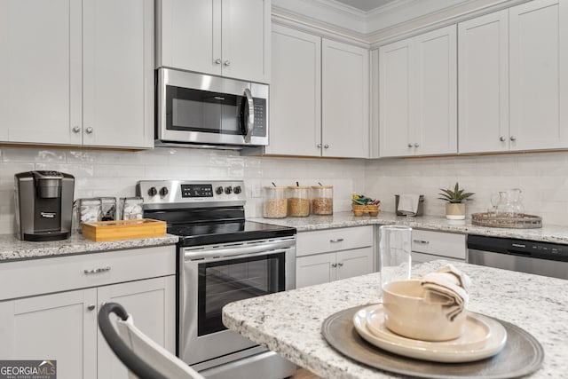 kitchen with stainless steel appliances, white cabinetry, decorative backsplash, and light stone countertops