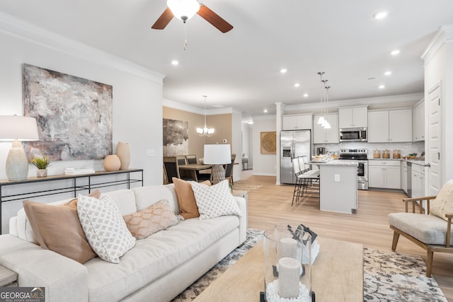 living room with ceiling fan with notable chandelier, light hardwood / wood-style floors, and crown molding