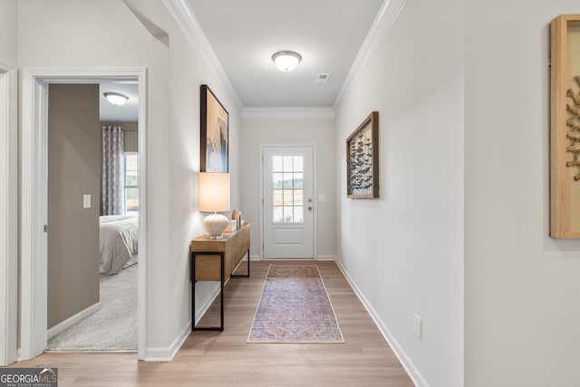 doorway to outside with ornamental molding, baseboards, visible vents, and light wood finished floors