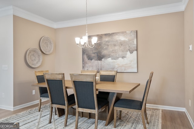 dining room with wood-type flooring, crown molding, and a notable chandelier