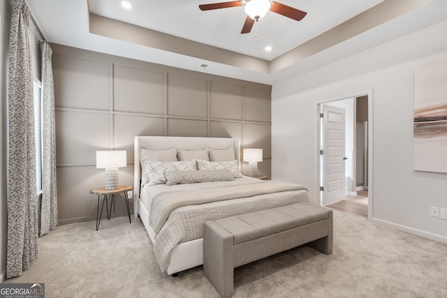 carpeted bedroom with a tray ceiling and ceiling fan