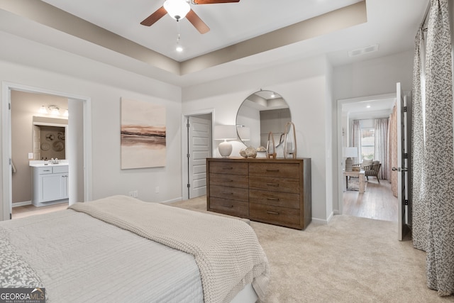 bedroom featuring light colored carpet, a tray ceiling, visible vents, and baseboards