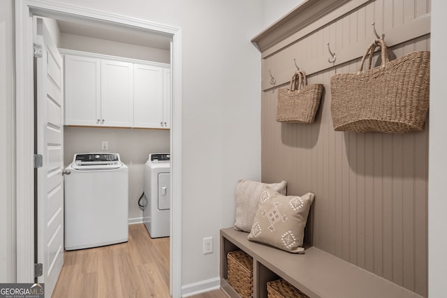 clothes washing area featuring washing machine and clothes dryer, cabinets, and light hardwood / wood-style floors