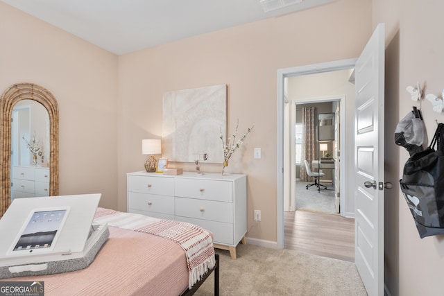 bedroom with baseboards, visible vents, and light colored carpet