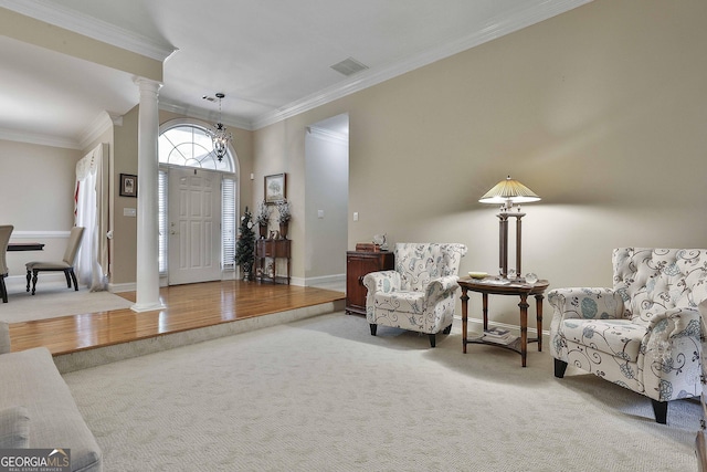 foyer entrance with carpet, ornate columns, crown molding, and a chandelier