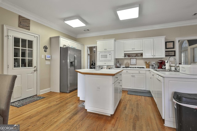 kitchen featuring sink, ornamental molding, a kitchen island, white cabinetry, and stainless steel appliances