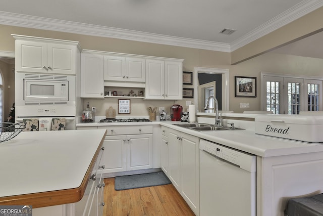 kitchen featuring kitchen peninsula, white appliances, white cabinetry, and sink