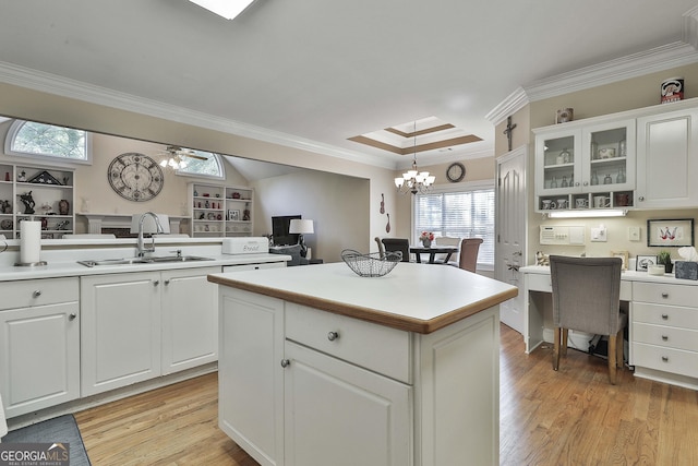 kitchen featuring white cabinets, decorative light fixtures, a center island, and crown molding