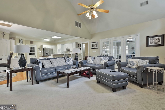 carpeted living room featuring ceiling fan, ornamental molding, high vaulted ceiling, and french doors