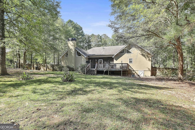 rear view of property featuring a lawn and a deck