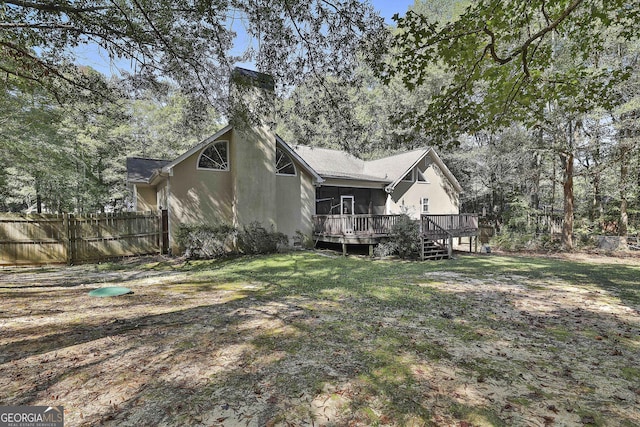 rear view of house with a lawn and a deck