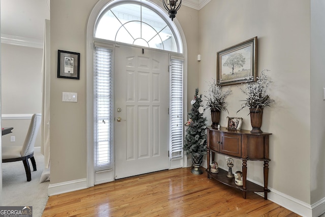 foyer entrance with light hardwood / wood-style floors and ornamental molding