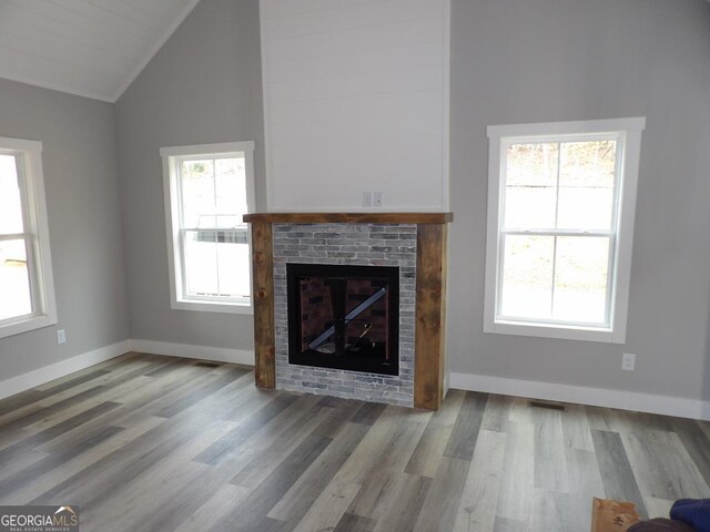 unfurnished living room with ceiling fan, a large fireplace, high vaulted ceiling, and light hardwood / wood-style floors