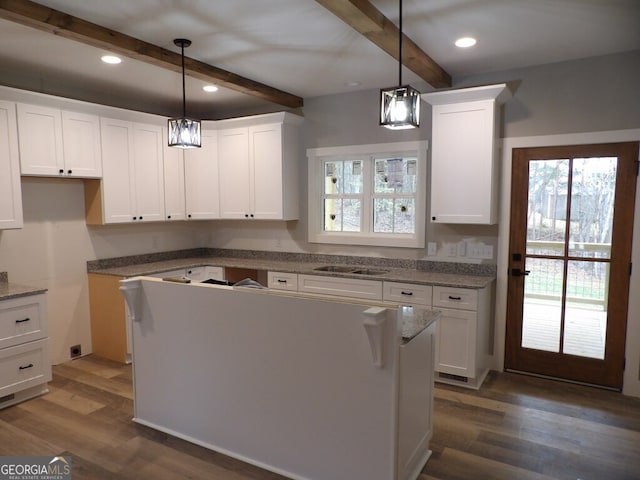 kitchen with beam ceiling, dark wood-type flooring, white cabinets, and pendant lighting