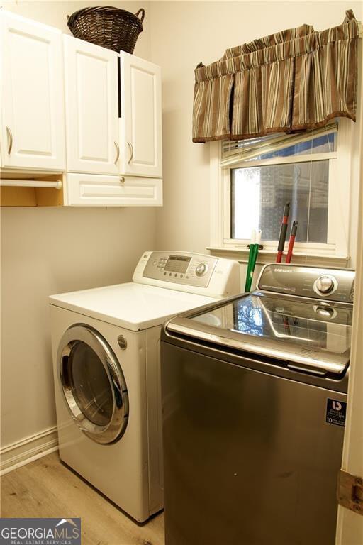 washroom featuring separate washer and dryer, cabinets, and light hardwood / wood-style floors