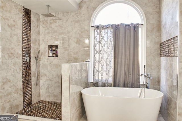 bathroom with tile walls and independent shower and bath