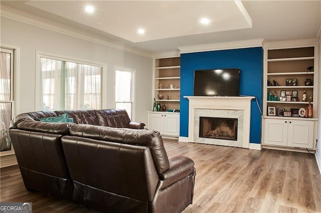 living room with built in shelves, crown molding, a fireplace, and hardwood / wood-style flooring